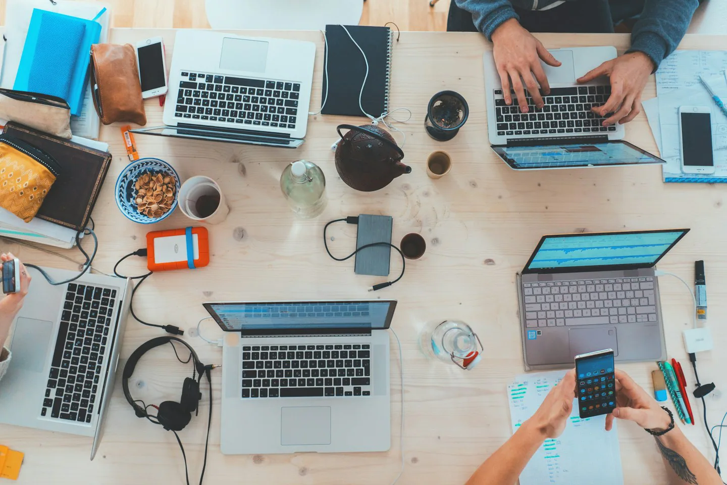Gemeinsamer Arbeitstisch mit Laptops und Notizen von oben