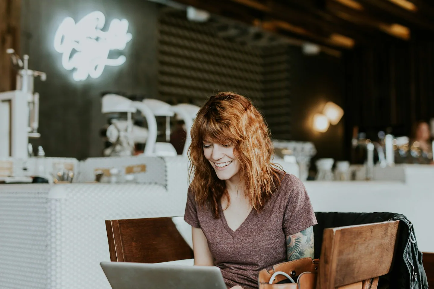 Eine Frau arbeitet konzentriert am Laptop in einem Café