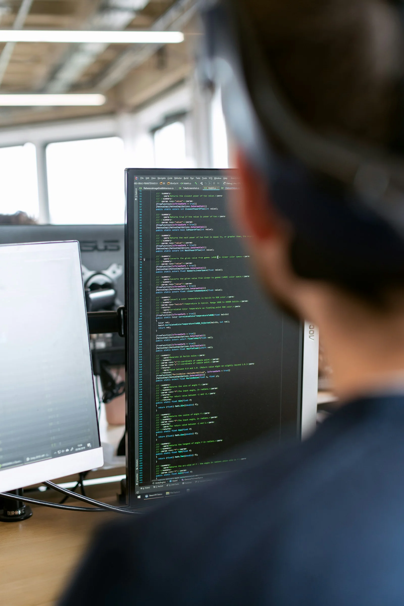 Blick über die Schulter eines Mannes auf Programmcode am Bildschirm.