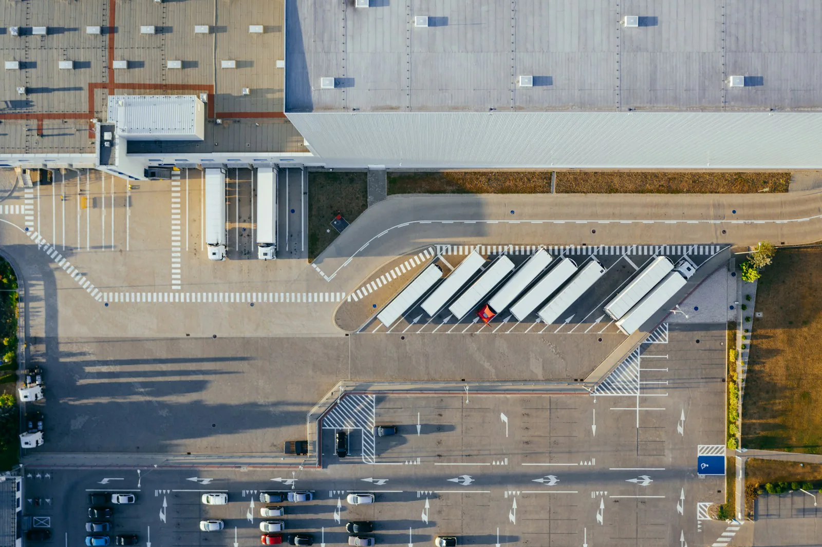 Luftaufnahme einer Logistikhalle mit Lkw an den Laderampen.