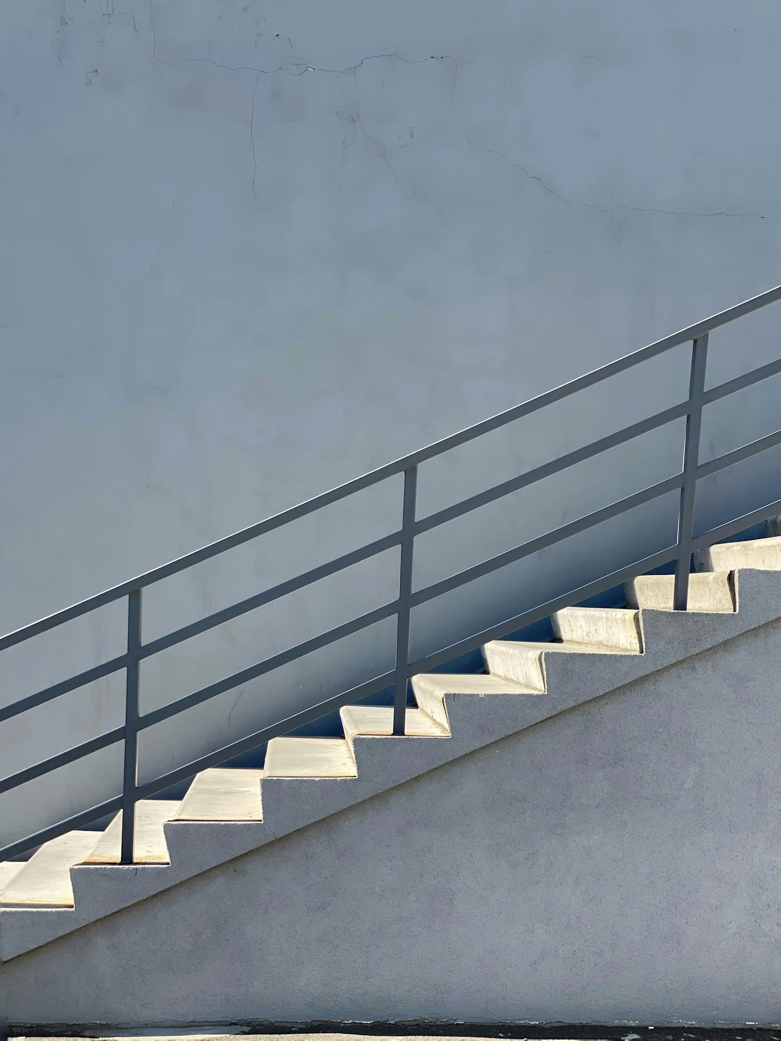 Eine helle Betontreppe mit Metallgeländer führt nach oben.