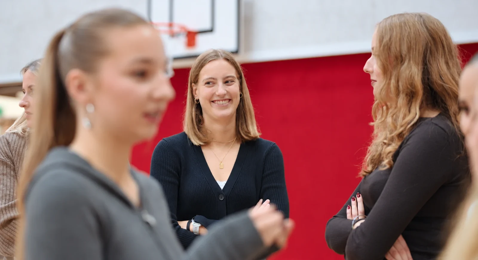 Eine junge Frau lacht im Gespräch mit anderen Studierenden.
