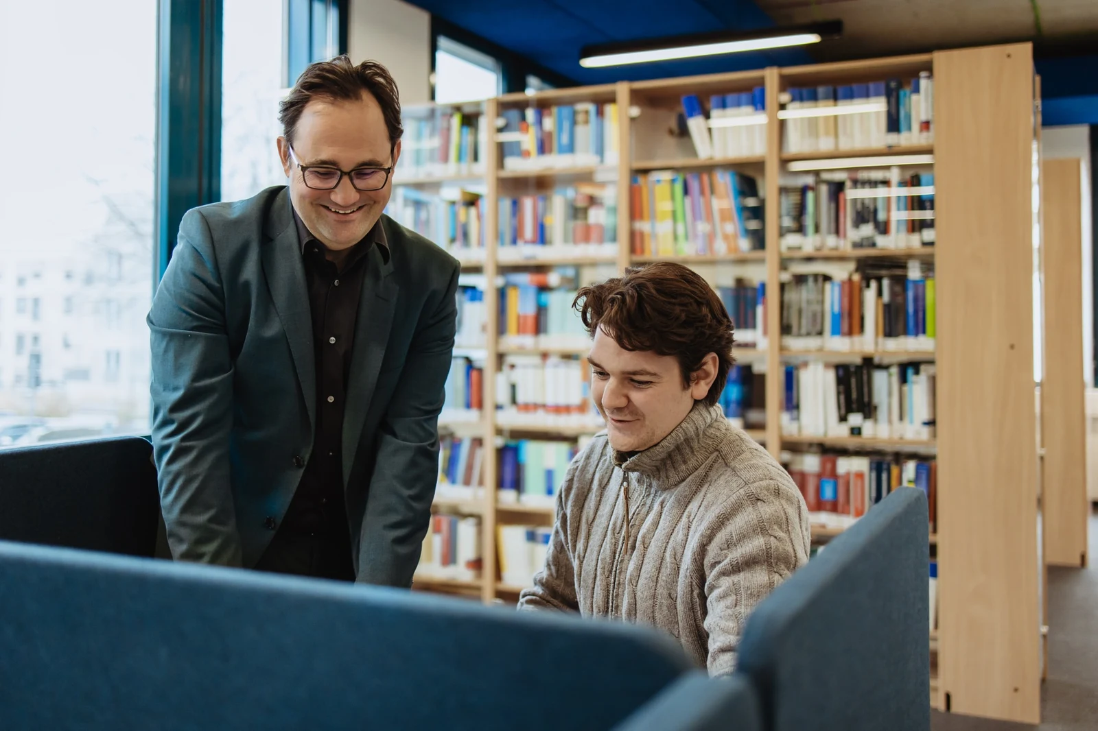 Ein junger Mann und ein Hochschulmitarbeiter im Austausch am Campus.