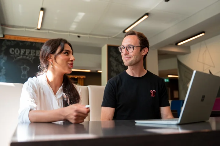 Persönlicher Austausch am Tisch mit Laptops im Campus-Café