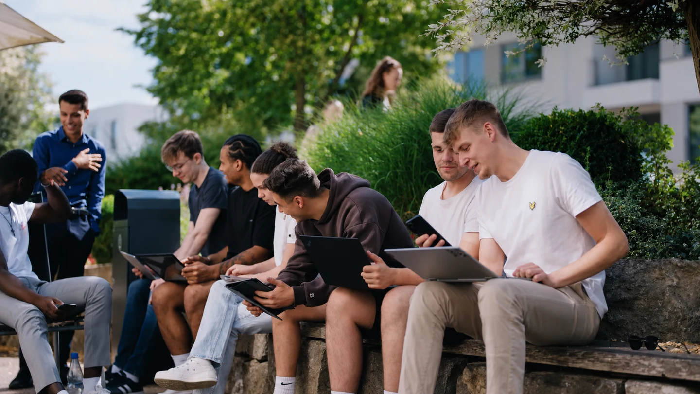 Junge Studierende arbeiten gemeinsam mit Tablets auf dem Campus