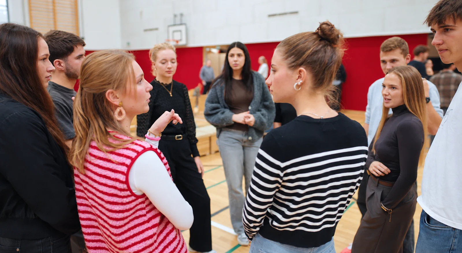 Studierende tauschen sich bei einer Gruppenaufgabe in der Sporthalle aus
