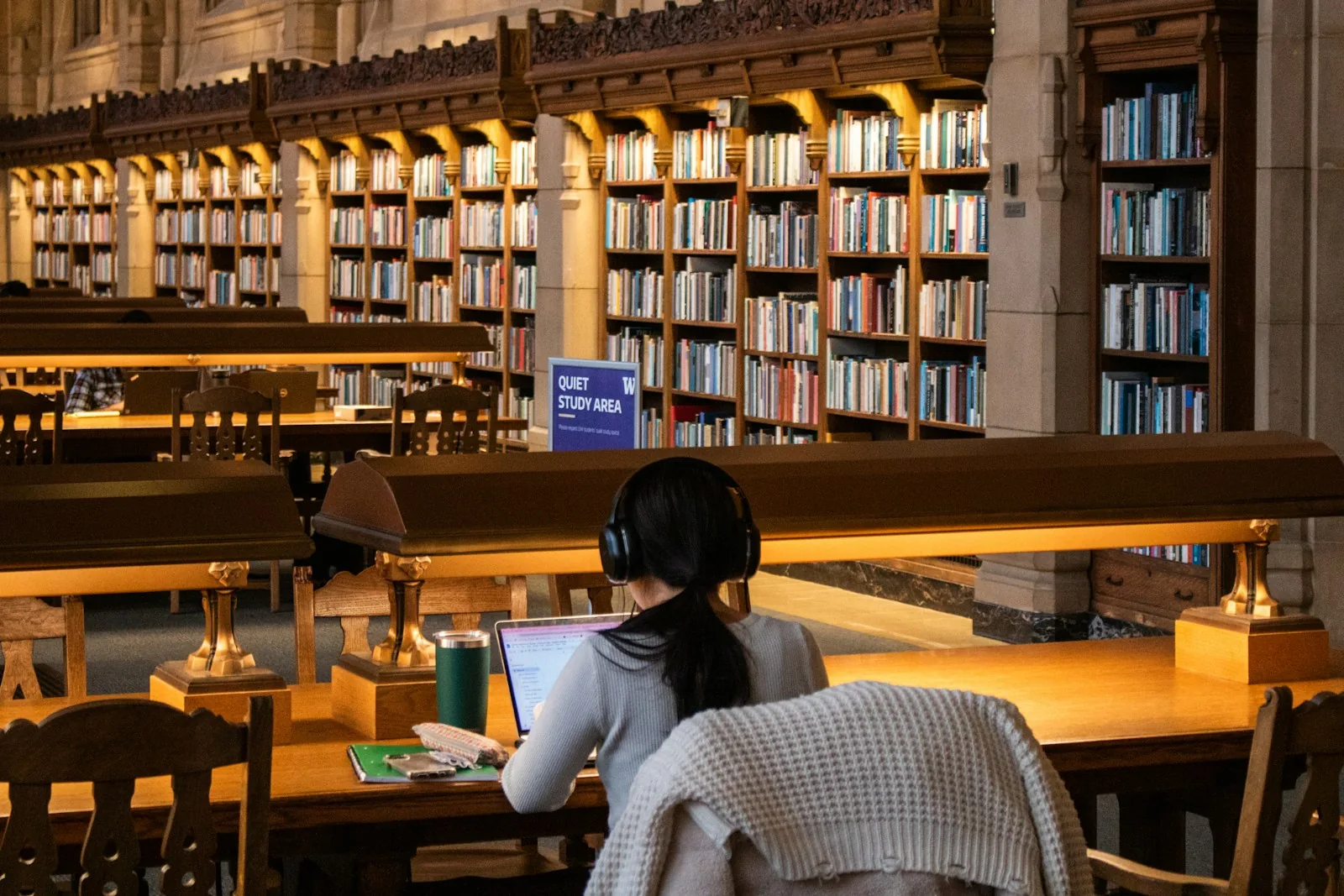Eine Studentin arbeitet mit Kopfhörern in einer Bibliothek.